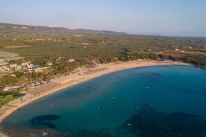 Vista aèria d'una zona costanera amb platja, edificis i vegetació.