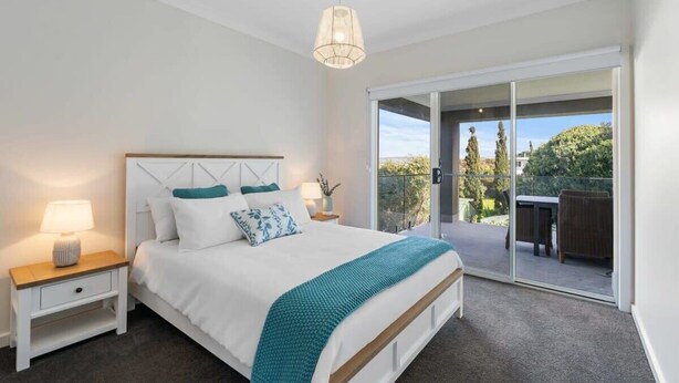 A bedroom with a bed, nightstands, a hanging light, and a sliding glass door to an outdoor area. - 13A Elliot Avenue, Hayborough – Sea Views, Walk to Beach, Wi-Fi & Bikeway (Hayborough)