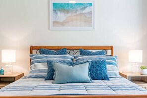 A bed with a striped blue and white bedspread, multiple pillows, and a wooden headboard.