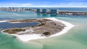 An aerial view of a coastal area with a small island, clear waters, and a distant cityscape with high-rise buildings. - Caribe Resort | Lazy River | Indoor & Outdoor Pools | Hot Tubs | Sleeps 14 (Orange Beach)