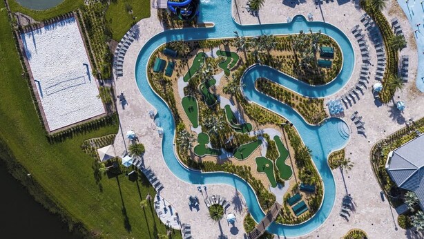 Vista aérea de un resort con piscina serpenteante, varias zonas de descanso y un edificio aparte con piscina.