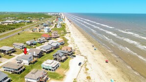 Une zone résidentielle côtière, avec des maisons le long de la plage, un ciel dégagé et une route bien visible.