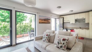 Una sala moderna con un sofá, una mesa de comedor y una zona de cocina con armarios y un televisor.