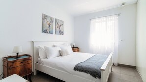 Un dormitorio con una cama grande, una mesita de noche y una ventana con cortinas.