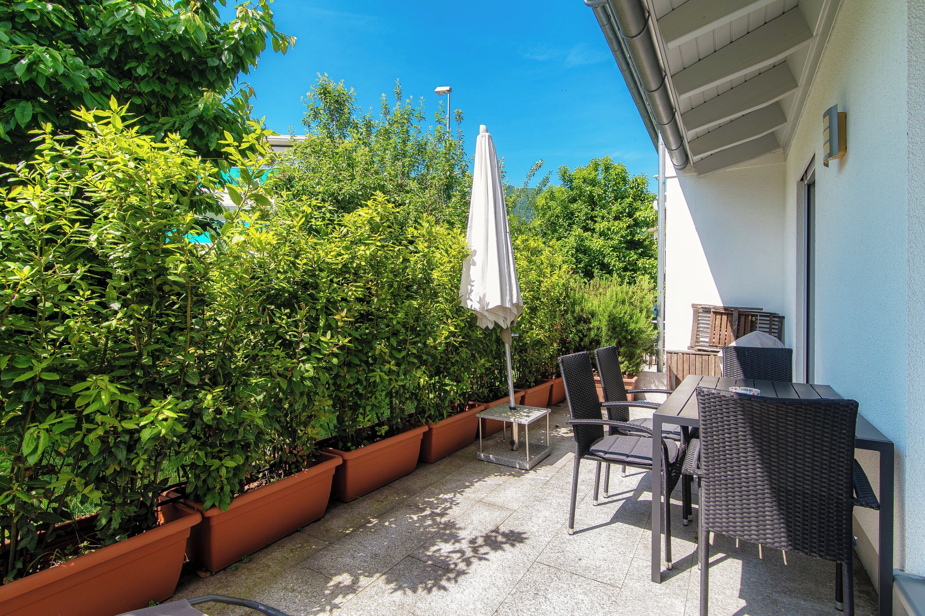 A patio with outdoor furniture, a grill, and potted plants.