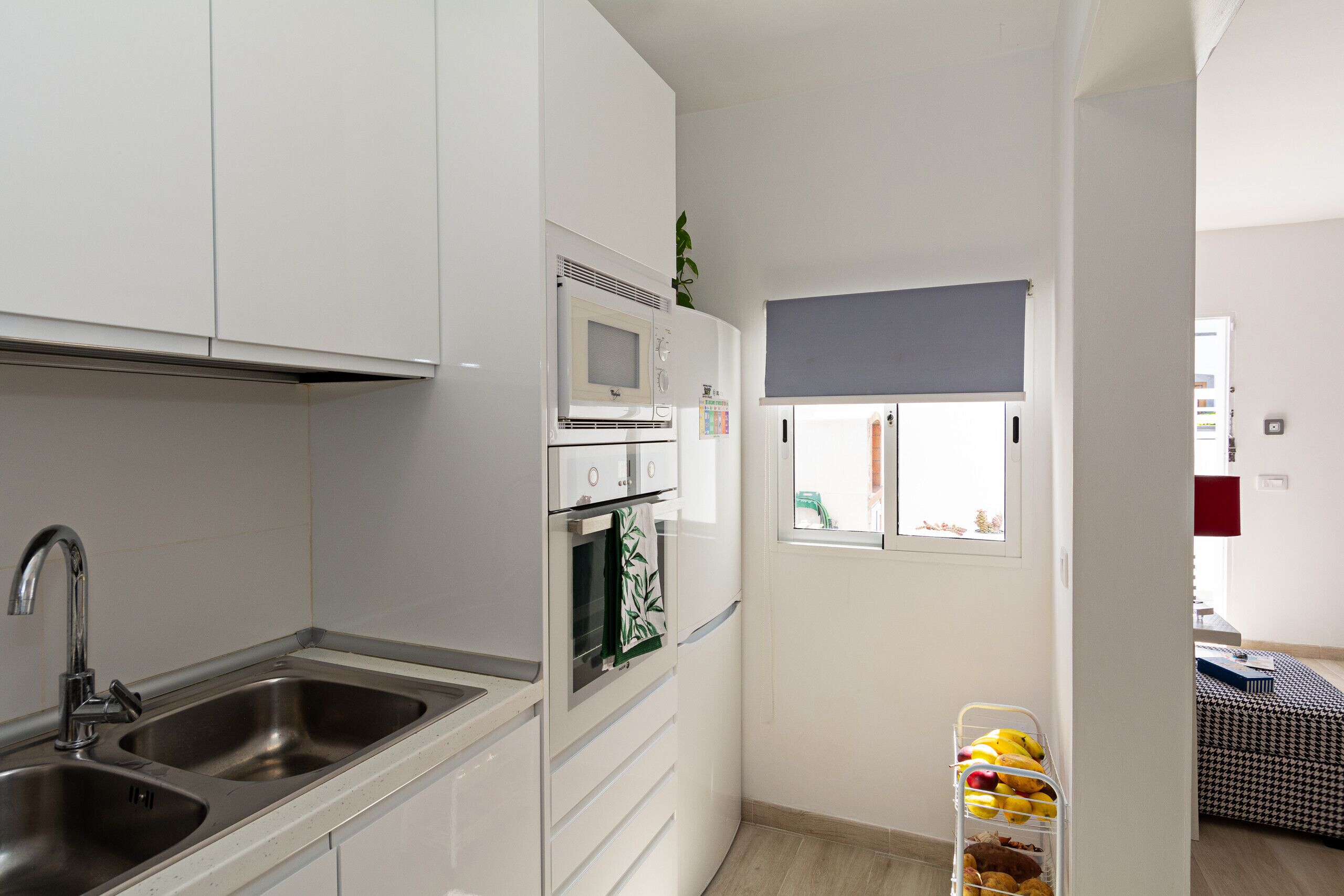 A modern kitchen with stainless steel appliances, a double sink, and a small window with a view.