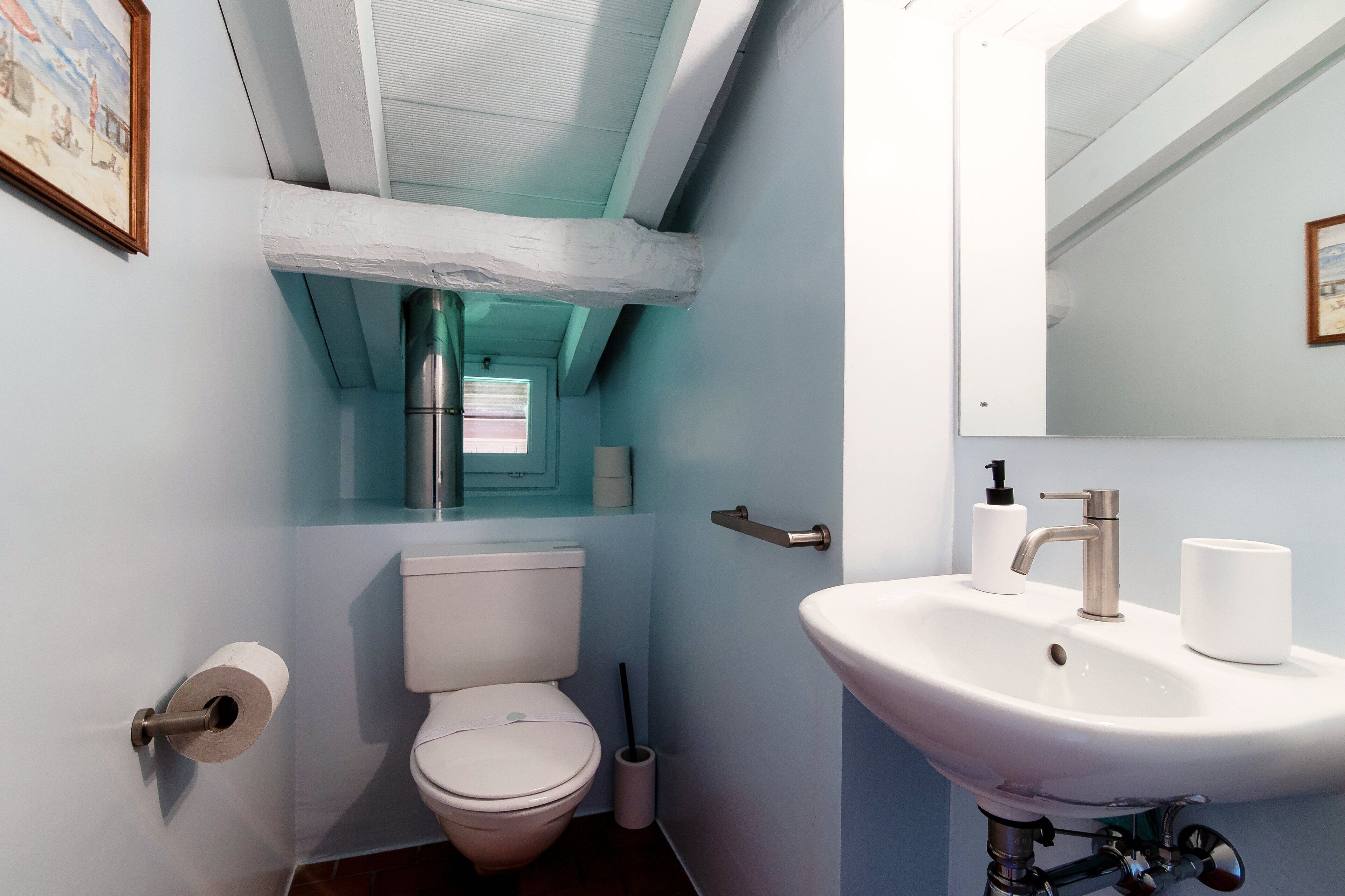 A bathroom with a toilet, sink, and mirror.