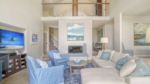 A spacious living area with a high ceiling, a fireplace, and a balcony with a railing. - New Listing in popular neighborhood (Kiawah Island)