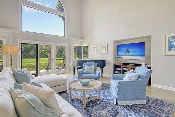 A spacious living room with a large TV, comfortable seating, and a piano. - New Listing in popular neighborhood (Kiawah Island)
