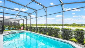 A covered swimming pool with a view of a lake and greenery.