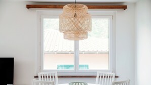 A dining area with a round white table, white chairs, and a woven pendant light. - Il Nido di Maria (Losone)