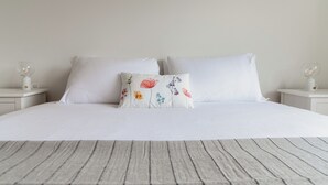 A neatly made bed with white bedding and a single decorative pillow with floral patterns. - Il Nido di Maria (Losone)