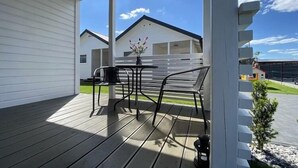Un espace extérieur abrité, doté d’une terrasse en bois, d’une table avec des chaises et d’une petite plante en pot.