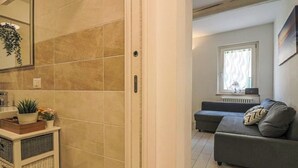 Un soggiorno moderno con un divano grigio, una finestra con tende e un termosifone.