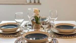 Una tavola imbandita con piatti, ciotole e bicchieri da vino, e un vaso di fiori.