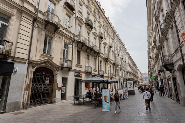 Una calle con edificios, mesas al aire libre y una cafetería.
