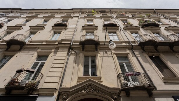 A building facade with multiple balconies, a central entrance with an arch, and a street sign above. - Garibaldi Ten by Wonderful Italy (Turin)