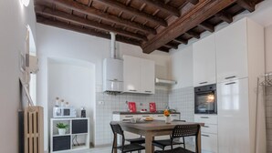 A compact kitchen with white cabinets, a wooden ceiling, and a tiled backsplash. - Garibaldi Ten by Wonderful Italy (Turin)
