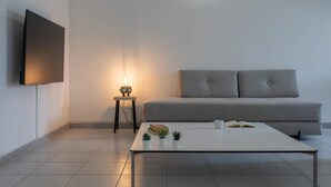 A modern living room with a sofa, a coffee table, a TV, and a small side table with a lamp. - Garibaldi Ten by Wonderful Italy (Turin)
