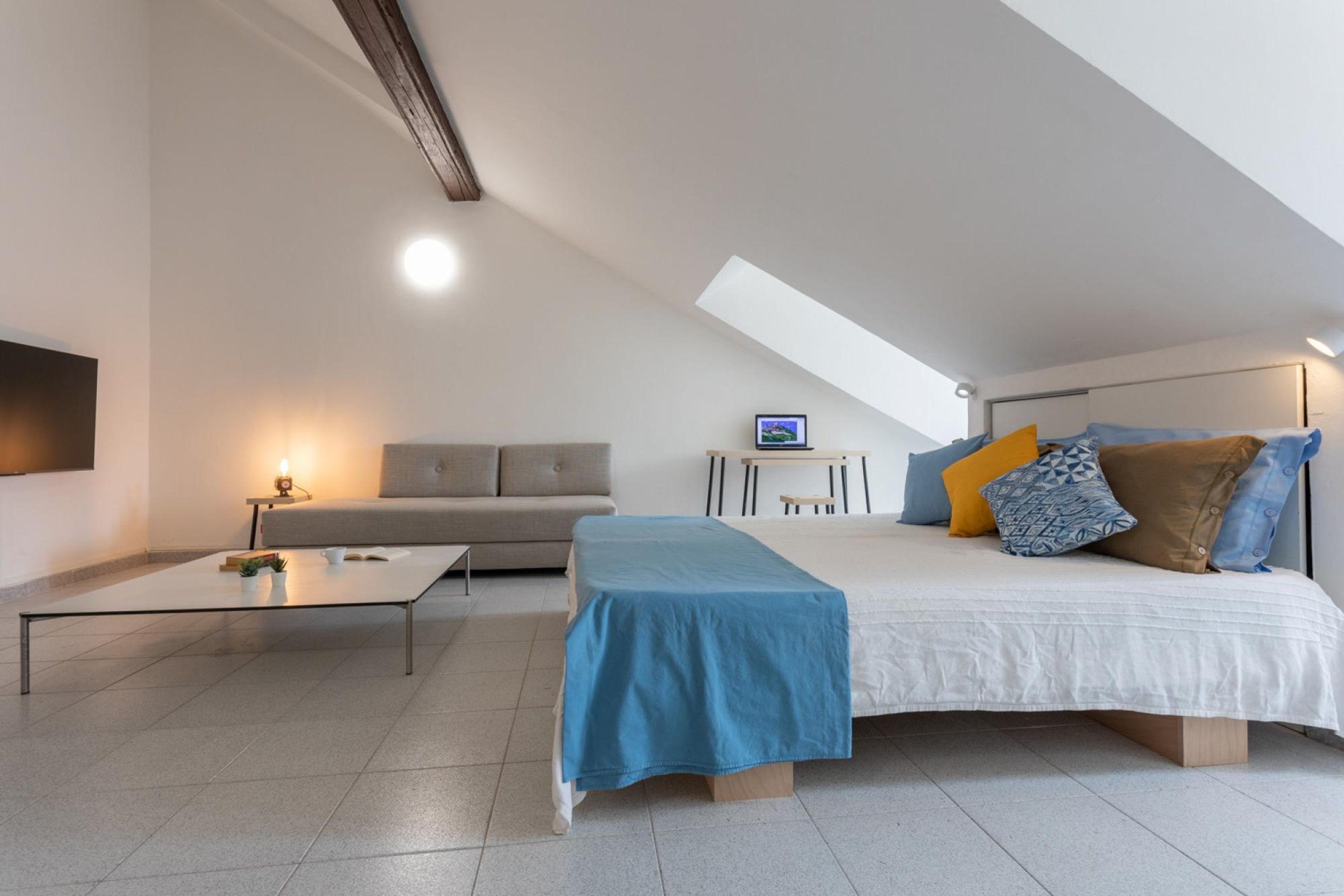 A modern bedroom with a bed, a sofa, a coffee table, and a desk.