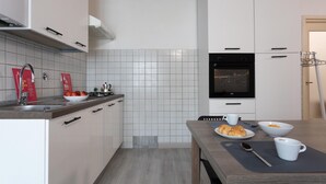 A modern kitchen with white cabinets, a stainless steel sink, and a built-in oven. - Garibaldi Ten by Wonderful Italy (Turin)