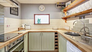 Una cucina con forno integrato, lavello e finestra vista verde.