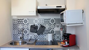 A kitchen with a stainless steel sink, a microwave, a coffee maker, and a patterned backsplash. - PLUTON 's near the gare station and markets (Saint-Quentin)