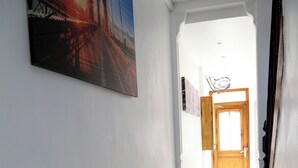 A hallway with a large painting of a bridge, a wooden door, and a tiled floor. - PLUTON 's near the gare station and markets (Saint-Quentin)