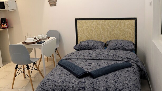 A neatly arranged bedroom with a bed, bedside table, and a small desk area with a chair. - PLUTON 's near the gare station and markets (Saint-Quentin)