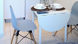 A compact kitchen with a patterned backsplash, a microwave, and a coffee maker. There is a dining table with chairs, and a small island with a wine glass and a cup. - PLUTON 's near the gare station and markets (Saint-Quentin)