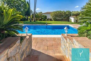 Relax by the serene pool surrounded by lush gardens and palm trees.