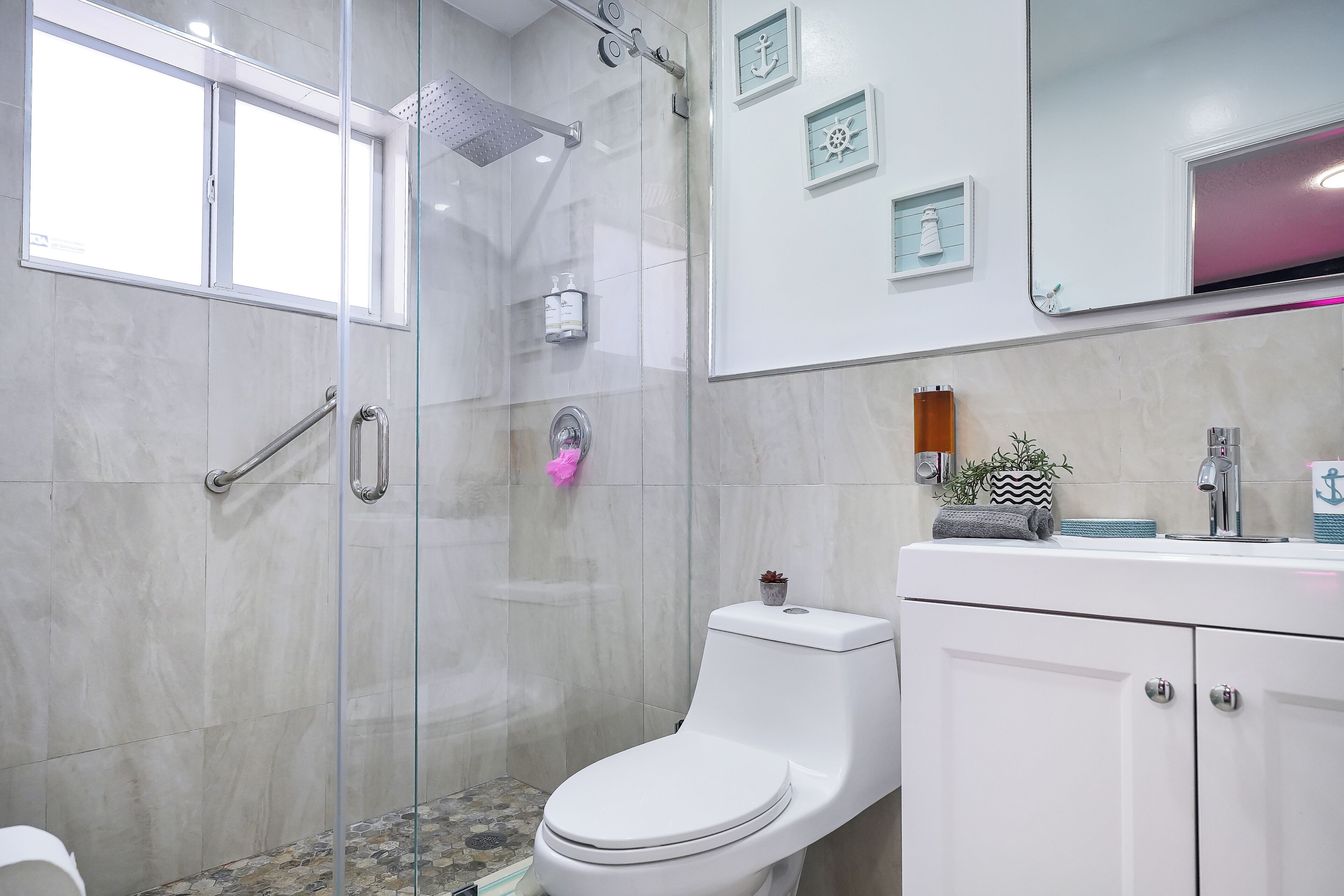 A modern bathroom with a glass-enclosed shower, a white toilet, and a vanity with a mirror.