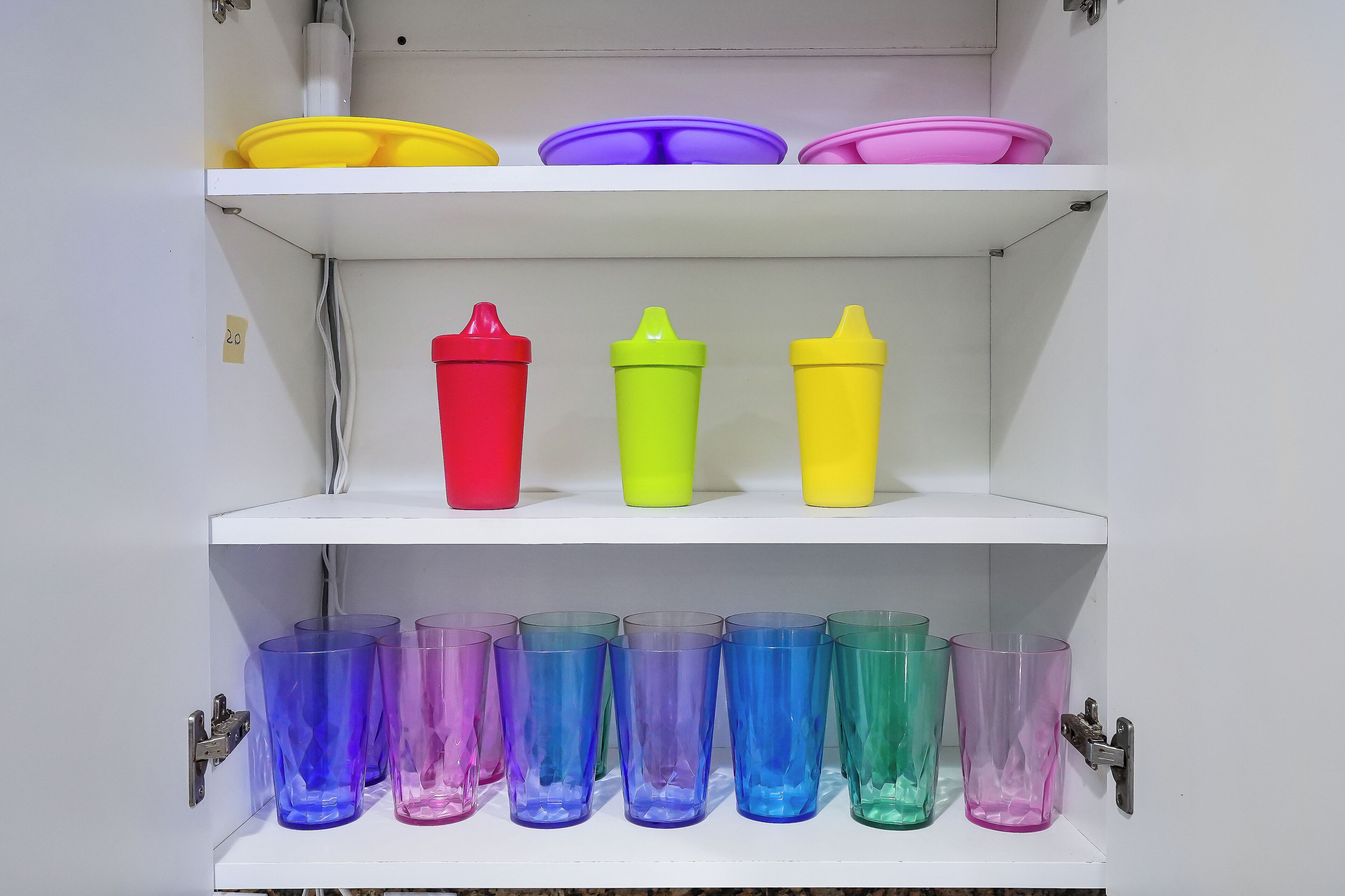 A storage unit with shelves containing various colored cups and containers.