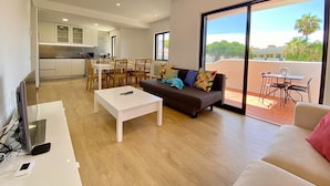 Um apartamento moderno com área de jantar, sala de estar com sofá e varanda com mesa e cadeiras.