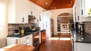 A modern kitchen with white cabinets, a black countertop, and a wooden ceiling.