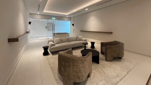 A modern, minimalist lounge area with a sofa, two armchairs, and a coffee table.