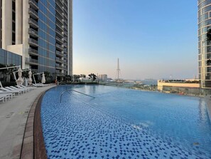 A rooftop infinity pool with a view of a tall building and a bridge in the distance. - Silkhaus 52|42, Dubai Marina (Dubai)