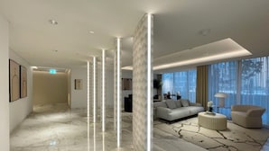 A modern hotel lobby with a marble floor, a sofa, a coffee table, and a large window with a city view.