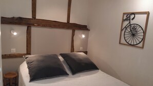 A bed with a white mattress and two dark pillows, a wooden headboard, and a wall-mounted bicycle decoration.
