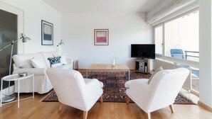 A modern living room with a white sofa, two white armchairs, a coffee table, and a TV. - Aldesago City View (Lugano)