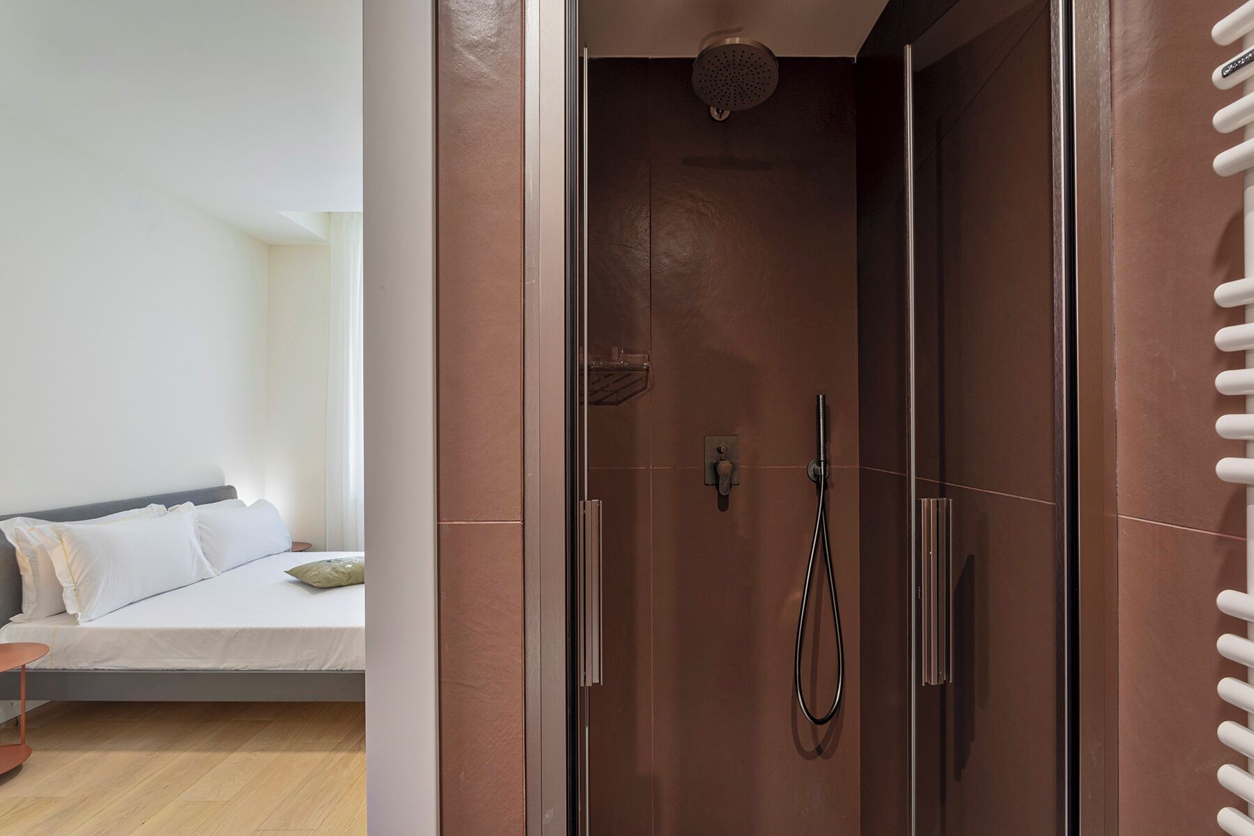 A modern bathroom with a glass shower enclosure, a visible showerhead, and a control panel.