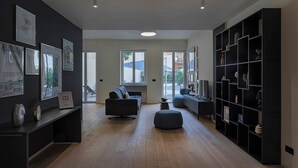 A modern living room with a dark color scheme, wooden flooring, and a large bookshelf. - Riviera Flavour Apartments II by Wonderful Italy (Santa Margherita Ligure)