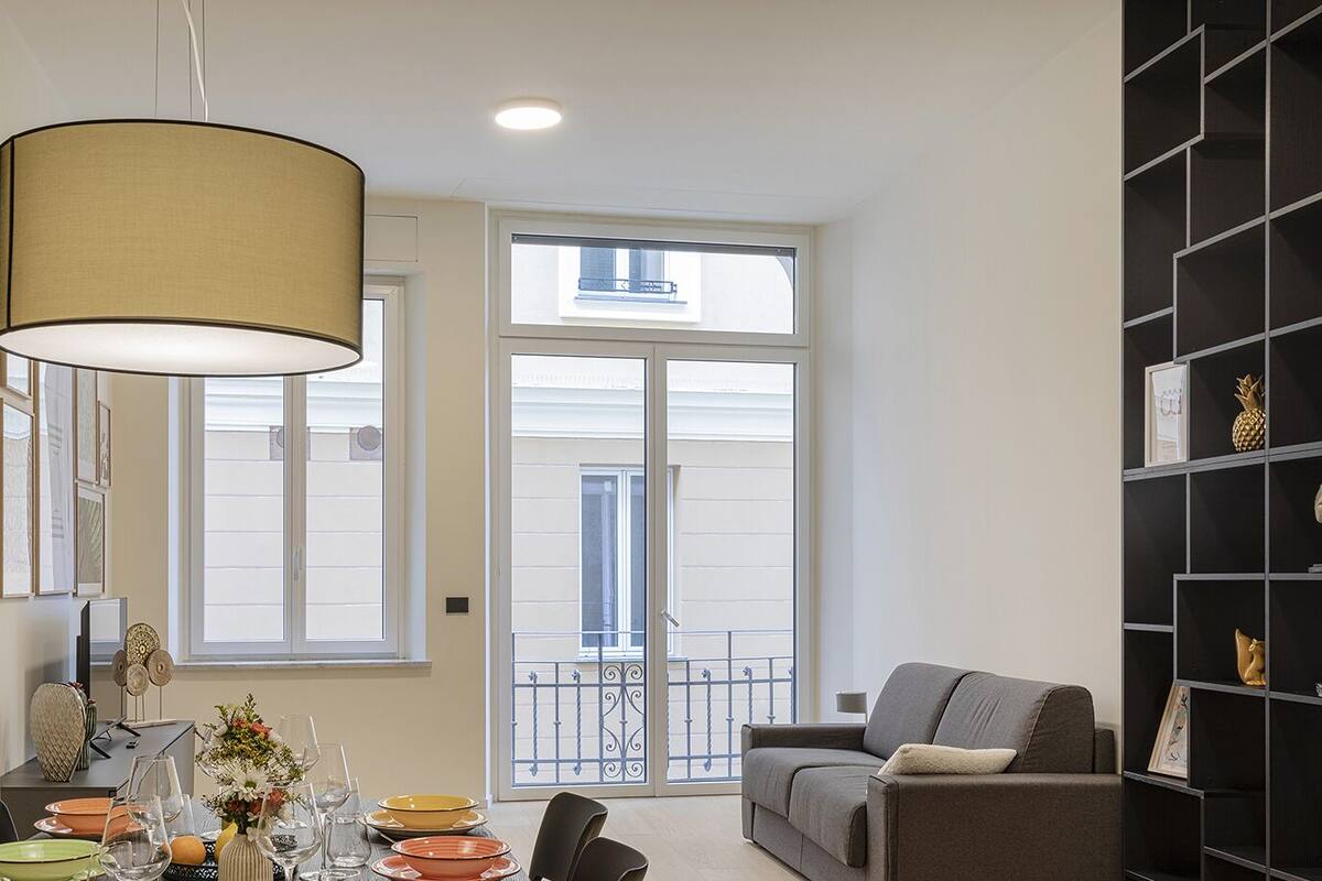 Un coin repas avec une table dressée pour quatre personnes, un canapé et une bibliothèque.