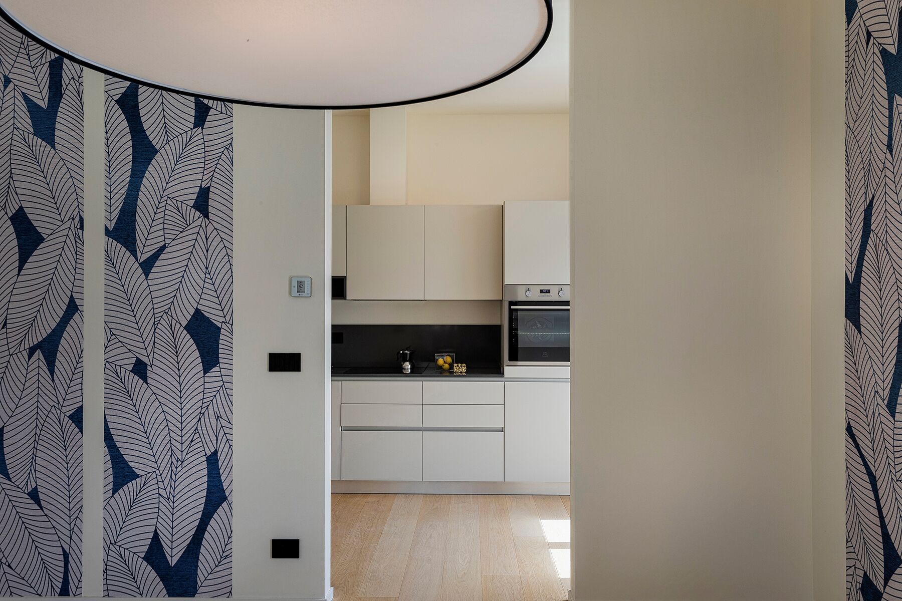 A modern kitchen with white cabinets, a black countertop, and a built-in oven.