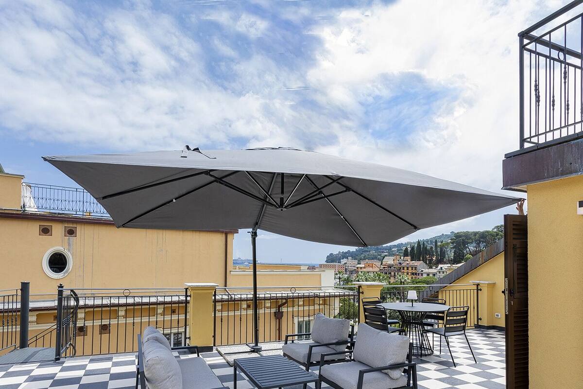 Une terrasse sur le toit, dotée d’un grand parasol, de sièges d’extérieur et d’un sol à carreaux.