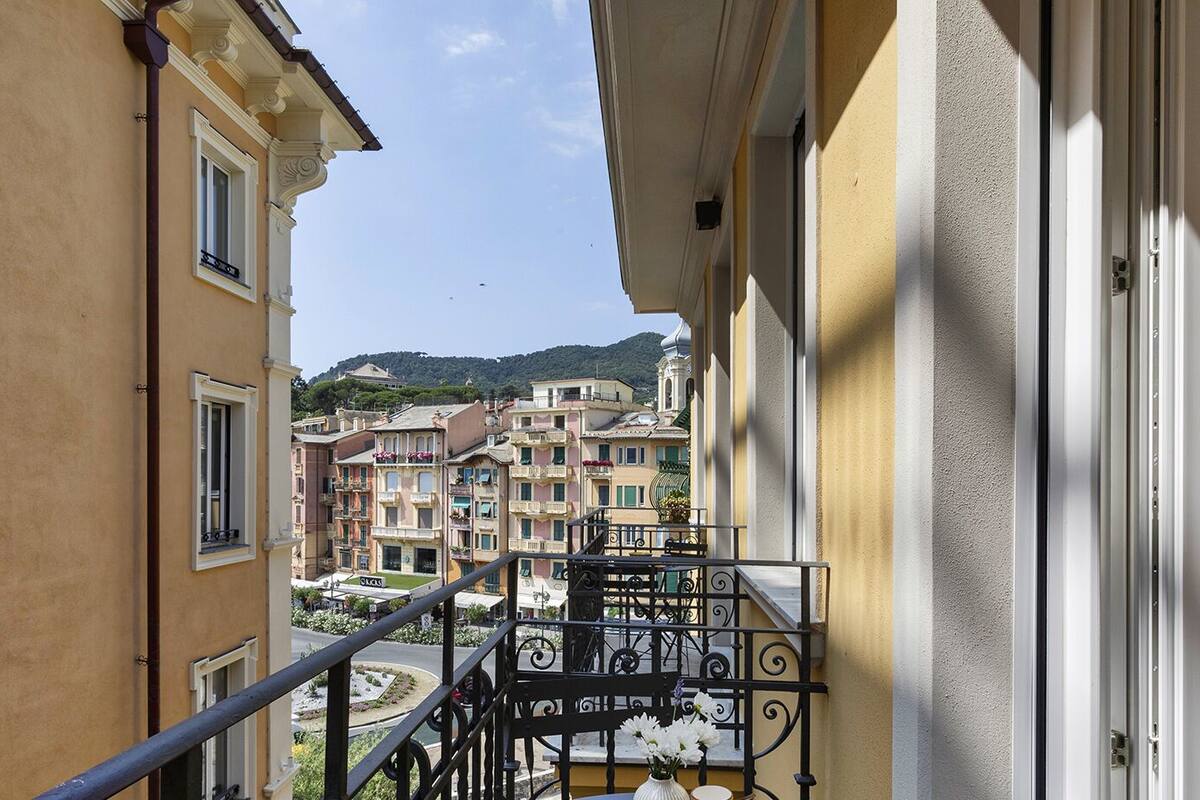 Un balcon offrant une vue sur des bâtiments aux couleurs vives et une colline au loin.