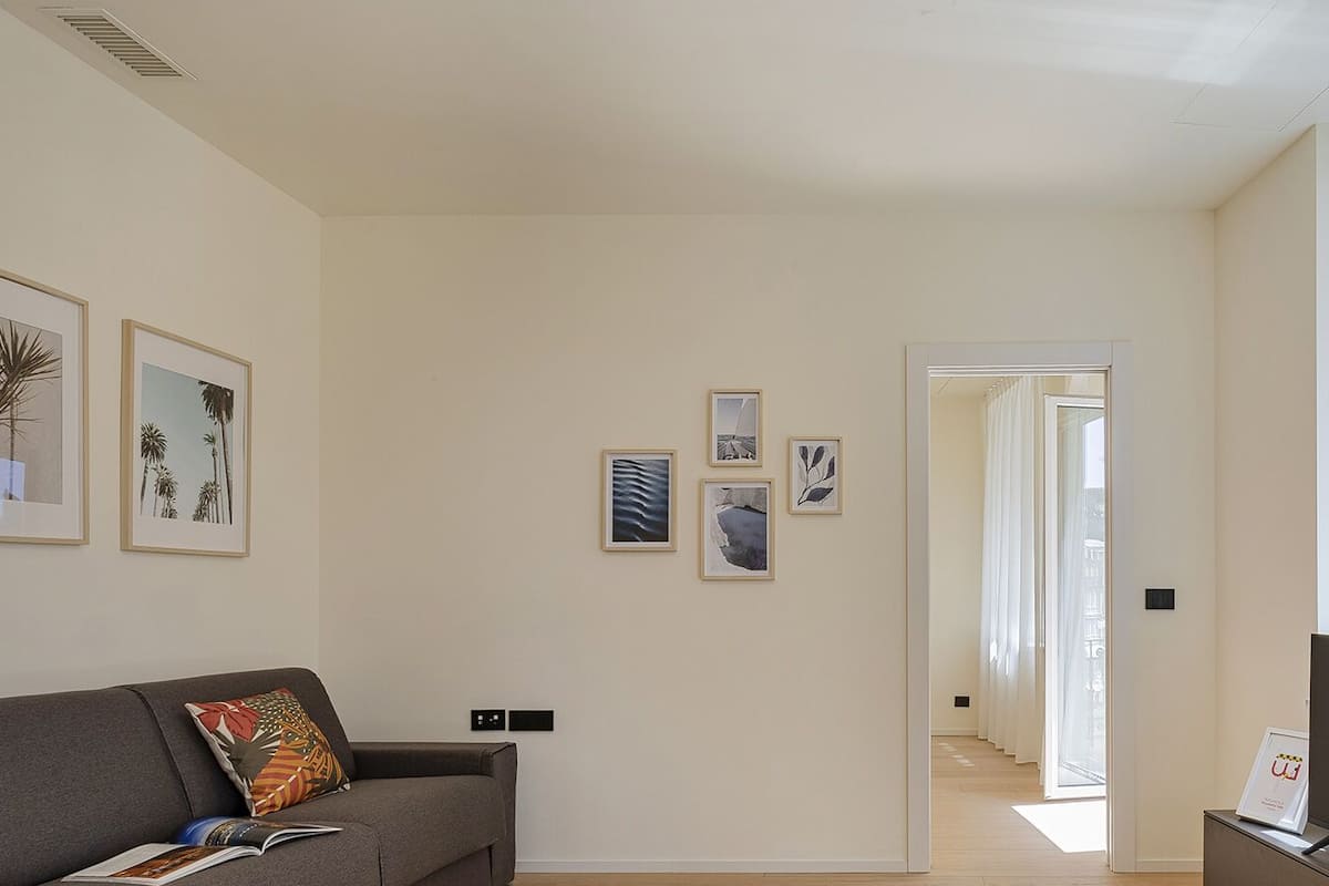 Un salon avec un canapé, un téléviseur et des œuvres d’art encadrées accrochées au mur.