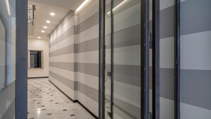 A hallway with striped walls, a tiled floor, and a door with a black frame. - Riviera Flavour Apartments II by Wonderful Italy (Santa Margherita Ligure)