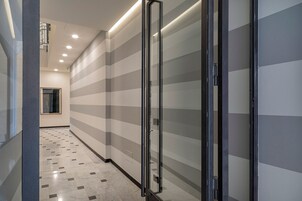 A hallway with striped walls, a tiled floor, and a door with a black frame.