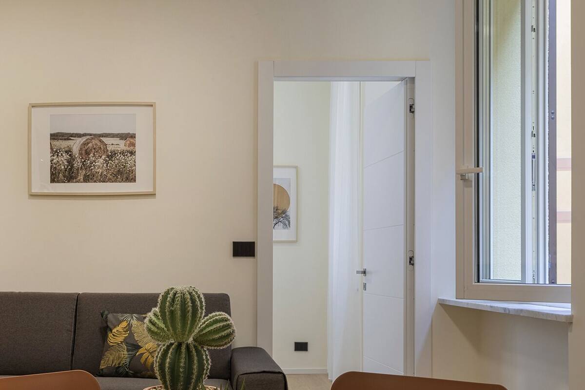 Un salon avec un canapé, un cactus et deux tableaux encadrés accrochés au mur.